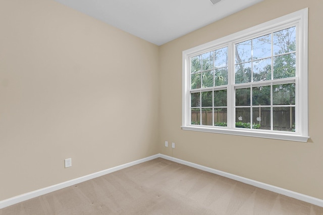 spare room featuring carpet floors, plenty of natural light, and baseboards