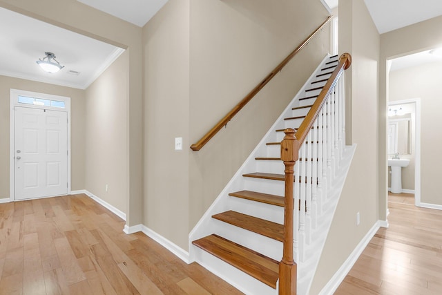 foyer featuring ornamental molding, stairway, light wood-style flooring, and baseboards