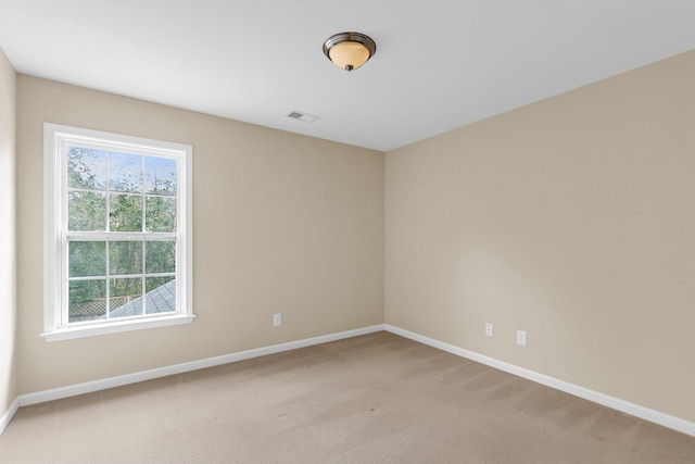 spare room with baseboards, visible vents, and light colored carpet