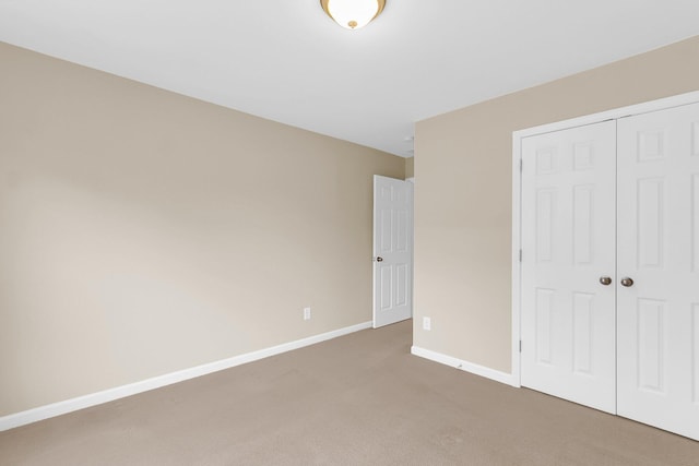 unfurnished bedroom featuring carpet floors, a closet, and baseboards