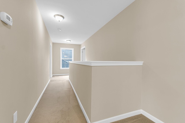 hallway featuring light carpet and baseboards