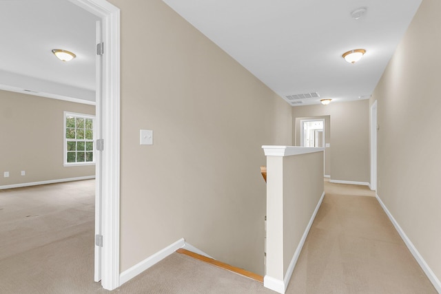 hall featuring light carpet, baseboards, visible vents, and an upstairs landing