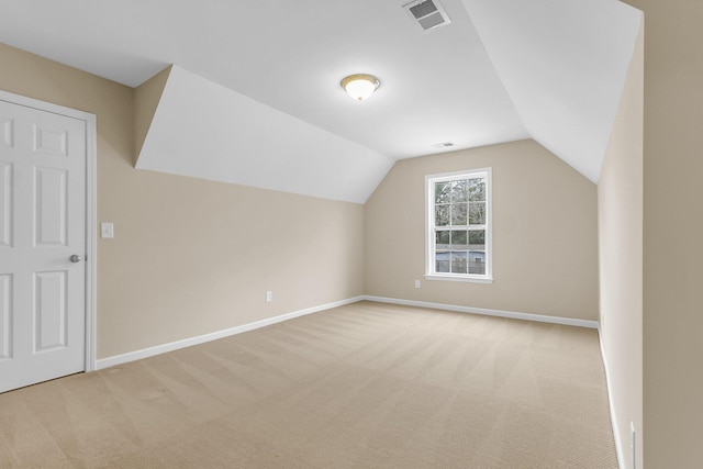 additional living space featuring light colored carpet, visible vents, lofted ceiling, and baseboards