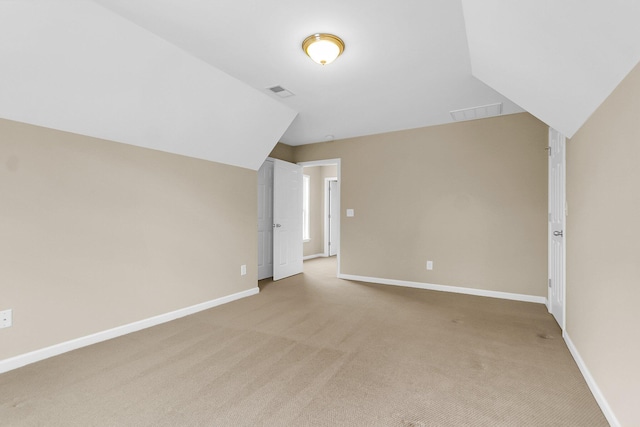 additional living space with lofted ceiling, light colored carpet, visible vents, and baseboards