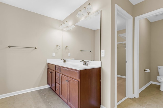 full bathroom featuring toilet, double vanity, baseboards, and a sink