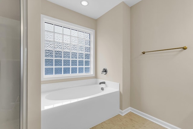 full bath featuring a garden tub, baseboards, and tile patterned floors