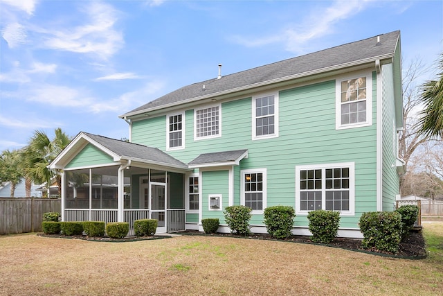 rear view of property featuring a sunroom, fence, and a lawn