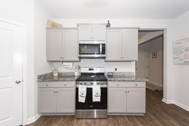 kitchen featuring dark wood-type flooring, stainless steel appliances, white cabinetry, and light stone counters