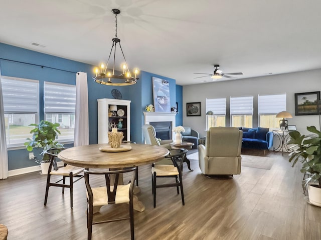 dining space featuring dark hardwood / wood-style flooring and ceiling fan with notable chandelier