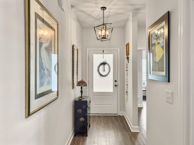 doorway to outside with dark hardwood / wood-style flooring and a chandelier