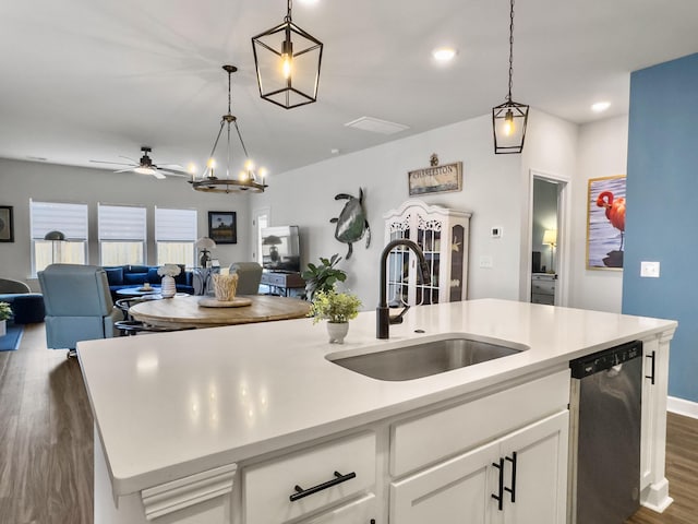 kitchen featuring decorative light fixtures, dishwasher, an island with sink, sink, and white cabinets