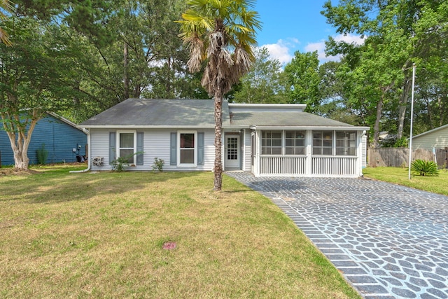 ranch-style house featuring a sunroom, fence, and a front yard