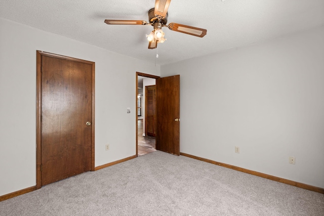 unfurnished bedroom featuring a closet, light carpet, a textured ceiling, and baseboards