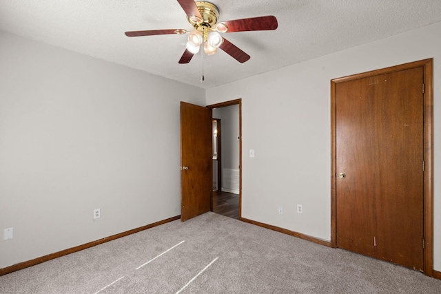 unfurnished bedroom with baseboards, ceiling fan, a textured ceiling, and light colored carpet