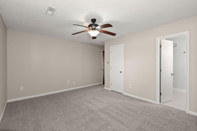 spare room featuring baseboards, a textured ceiling, visible vents, and light colored carpet