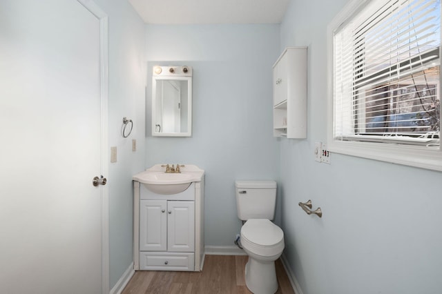 bathroom with toilet, wood finished floors, vanity, and baseboards