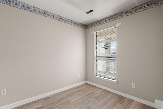 spare room featuring light wood-type flooring, visible vents, and baseboards