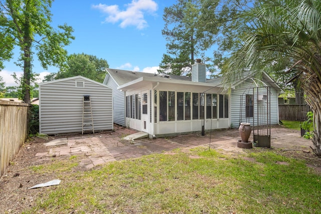 rear view of property featuring a patio, a chimney, a fenced backyard, and a sunroom