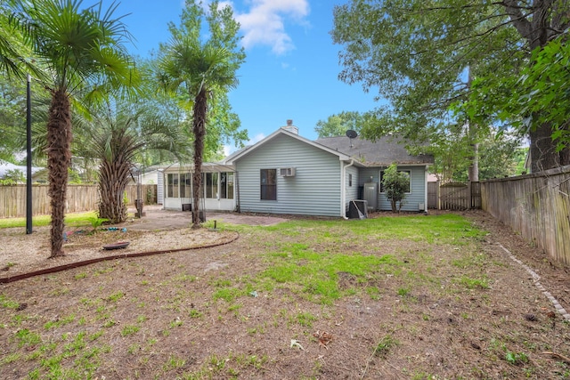 back of house with a sunroom, a fenced backyard, and a lawn