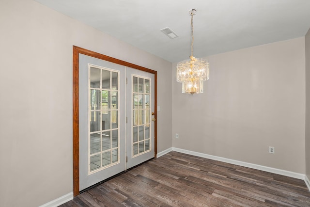 unfurnished dining area with an inviting chandelier, visible vents, baseboards, and dark wood-type flooring