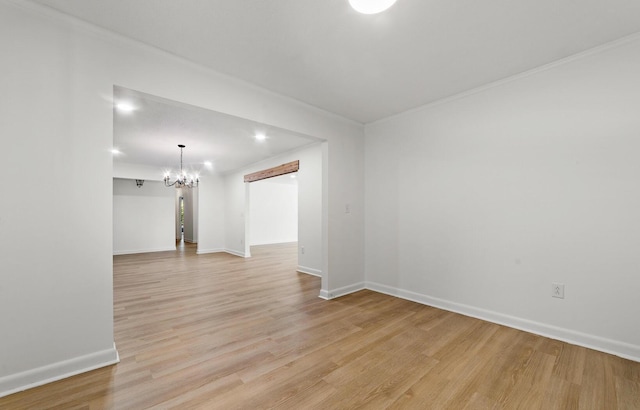 spare room featuring light hardwood / wood-style floors, an inviting chandelier, and ornamental molding