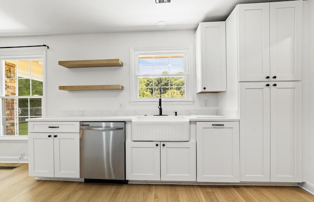 kitchen with white cabinets, light hardwood / wood-style flooring, stainless steel dishwasher, and sink