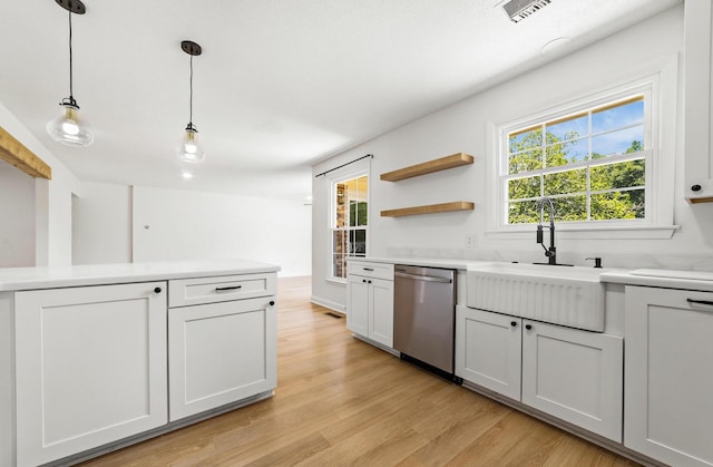 kitchen featuring pendant lighting, white cabinets, sink, stainless steel dishwasher, and light hardwood / wood-style floors