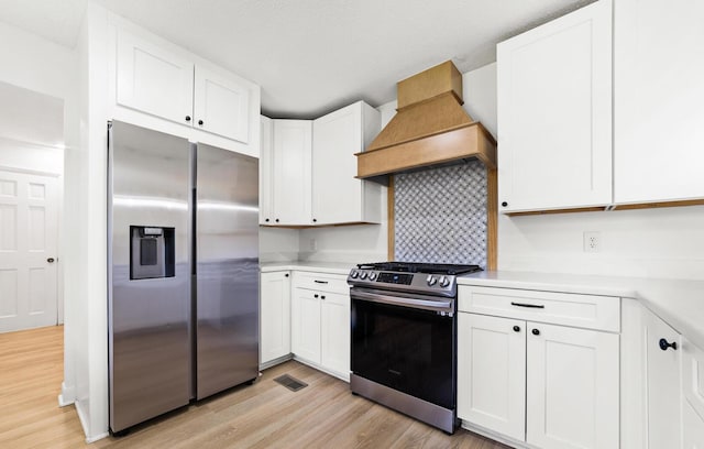 kitchen featuring white cabinets, custom range hood, and appliances with stainless steel finishes