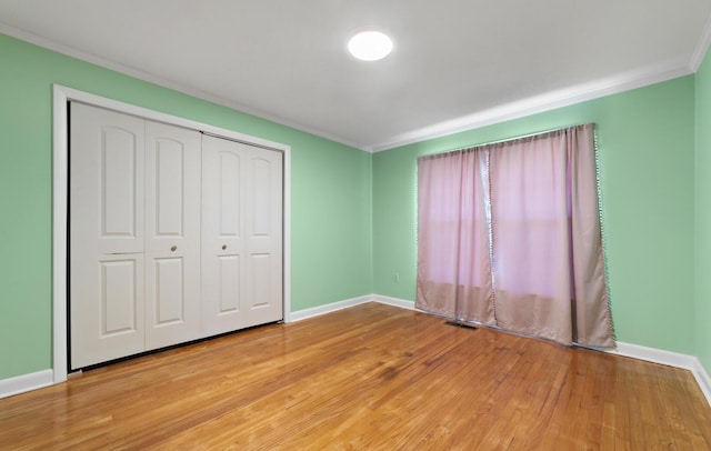 unfurnished bedroom featuring a closet, light hardwood / wood-style floors, and ornamental molding