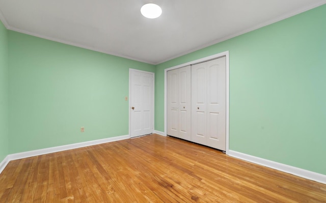 unfurnished bedroom with a closet, light hardwood / wood-style flooring, and ornamental molding