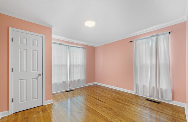 unfurnished room with ornamental molding and hardwood / wood-style flooring