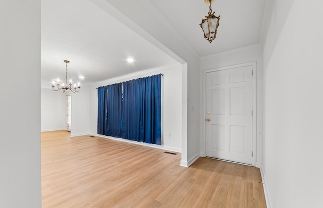 foyer with ornamental molding, wood-type flooring, and a notable chandelier