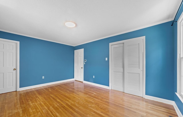 unfurnished bedroom featuring a closet, crown molding, light hardwood / wood-style flooring, and a textured ceiling