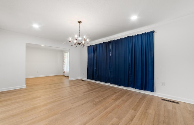 spare room with a chandelier and hardwood / wood-style flooring