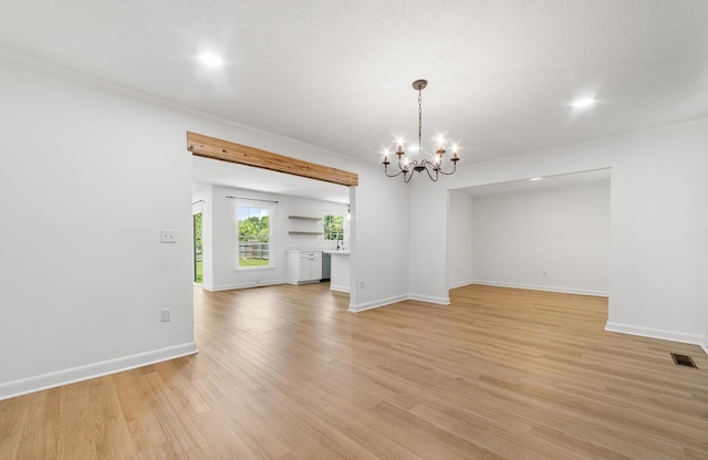 unfurnished living room with light hardwood / wood-style floors, a textured ceiling, and an inviting chandelier