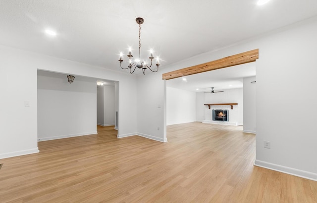 unfurnished living room featuring ceiling fan with notable chandelier, light wood-type flooring, and a brick fireplace