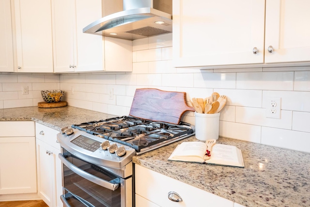 3707 Gambrill Ln, Mount Pleasant, SC 29466 - kitchen with wall chimney range hood, range with two ovens, tasteful backsplash, white cabinetry, and light stone counters