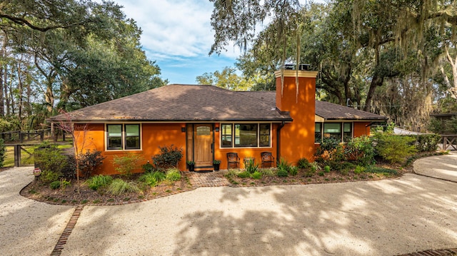 view of front of property featuring a chimney and roof with shingles