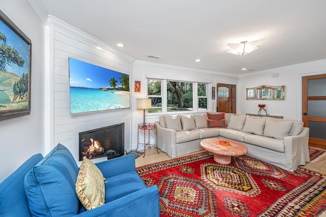 living area featuring recessed lighting, visible vents, ornamental molding, a large fireplace, and wood finished floors