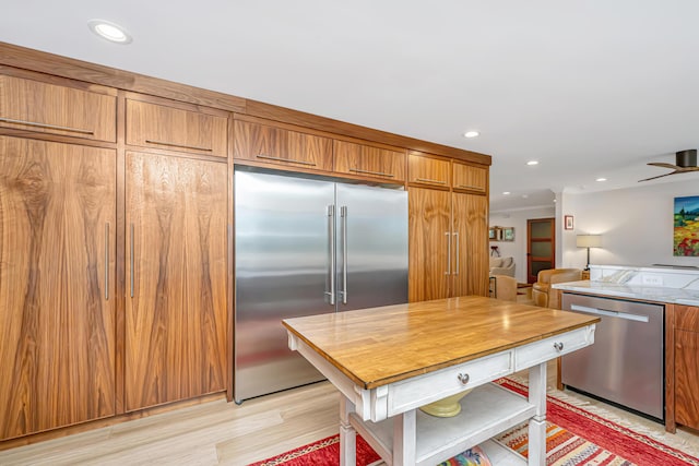 kitchen featuring brown cabinetry, light wood-style flooring, stainless steel appliances, light countertops, and recessed lighting