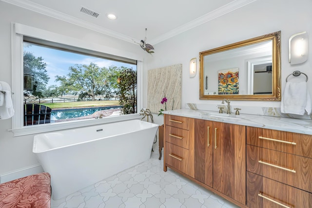 bathroom with visible vents, ornamental molding, vanity, a freestanding tub, and baseboards