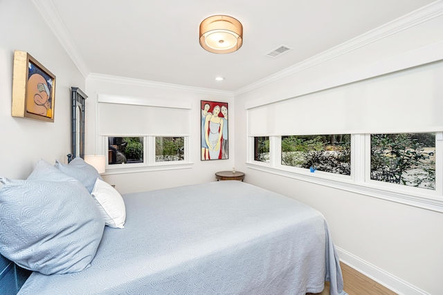 bedroom featuring multiple windows, wood finished floors, visible vents, and crown molding