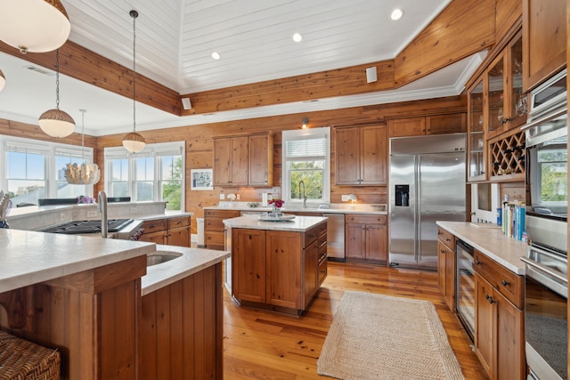 kitchen with appliances with stainless steel finishes, brown cabinets, a spacious island, and a healthy amount of sunlight