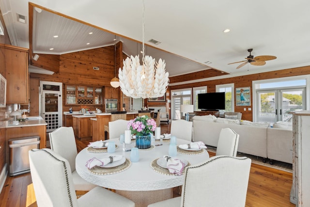 dining room with recessed lighting, wood finished floors, wooden walls, and visible vents