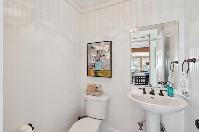 half bath with baseboards, a sink, and toilet
