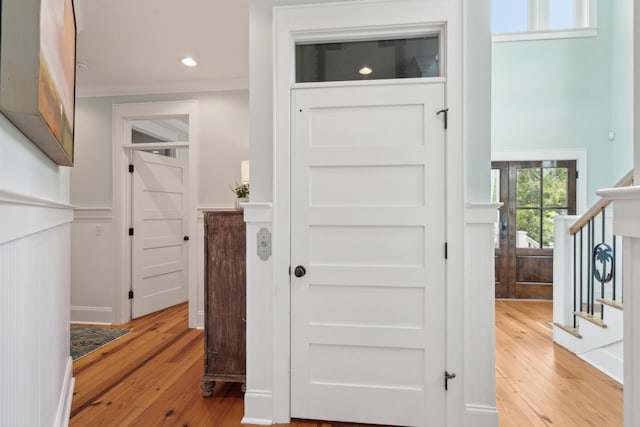 hallway with crown molding, recessed lighting, light wood-style flooring, and stairs