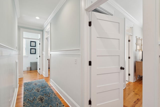 hall with crown molding, wainscoting, and light wood-style floors