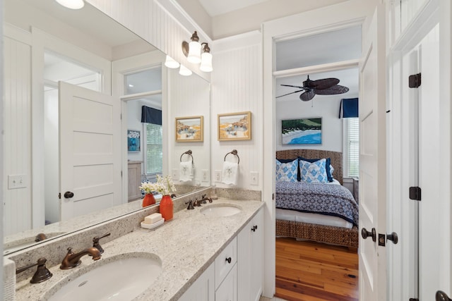 full bath with a sink, double vanity, a ceiling fan, ensuite bathroom, and wood finished floors