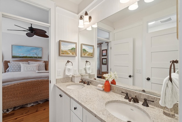 ensuite bathroom featuring ensuite bathroom, a sink, wood finished floors, and double vanity