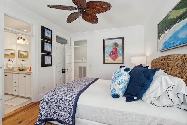 bedroom with crown molding, indoor wet bar, light wood-type flooring, and ensuite bath